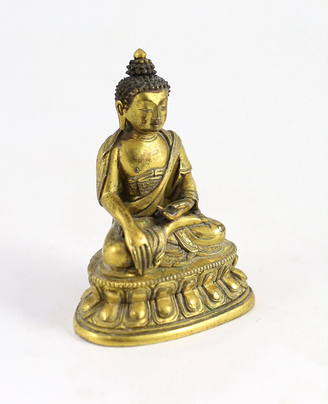 A small Tibetan gilt bronze seated figure of Buddha Shakyamuni, 18th century, 9.5cm high, lacking bowl in left hand
